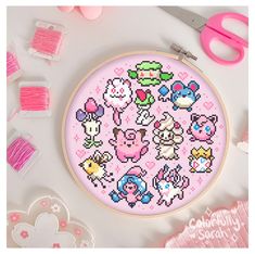 the cross stitch pattern is being displayed with scissors and other crafting supplies around it