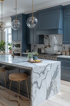 a kitchen with blue cabinets and marble counter tops, two stools in front of the island