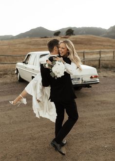 a bride and groom are dancing in front of a white truck on the side of the road