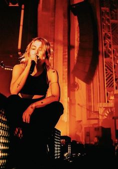 a woman sitting on top of a stage holding a microphone