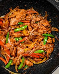 stir fry with meat, peppers and onions in a wok on the stove top