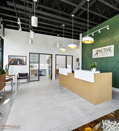 an office with green walls and white counter tops, yellow lights hanging from the ceiling