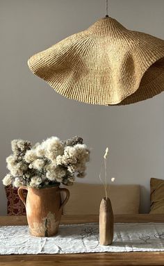 two vases with flowers in them are hanging from the ceiling above a dining room table