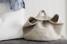 a white purse sitting on top of a gray couch