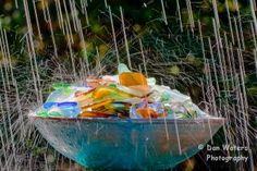 a blue bowl filled with lots of different colored plastic bottles and straws in the rain