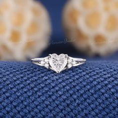 a heart shaped diamond ring sitting on top of a blue blanket