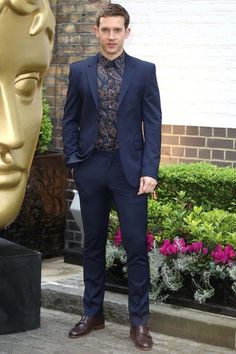 a man in a suit standing next to a statue