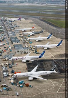 an aerial view of several airplanes parked at the airport terminal, with other planes on the tarmac in the background