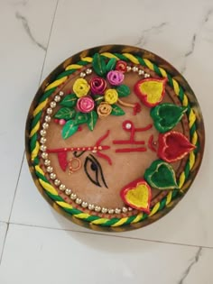 a cake decorated with flowers and leaves on top of a white tile floor next to a wall