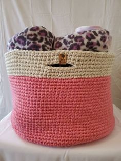 a pink and white crocheted basket with leopard print on the top, sitting on a table