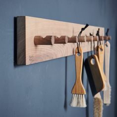 several wooden spoons hanging from hooks on a blue wall