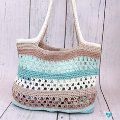 a crocheted bag sitting on top of a white wooden floor next to a wall