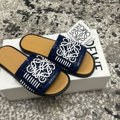 Loewe Anagram Bicolor Woven Flat Sandals Size 37 Loewe Anagram Basket, Designer Blue Slides For Summer, Luxury Blue Slides For Summer, Loewe Sandals, Loewe Egg Shoes, Luxury Blue Summer Slides, Crocs Wedges, Designer Blue Slides With Branded Insole, Leather Intrecciato Weave Slip-on Sandals