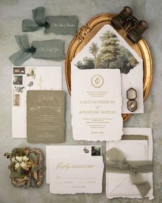 the wedding stationery is laid out in gold and white, along with other items