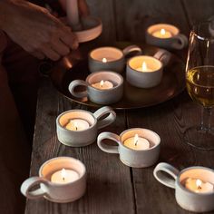 several tea lights on a wooden table with wine glasses