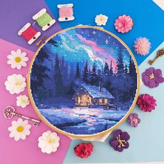 a cross stitch pattern with flowers and pins on it, next to a sewing needle