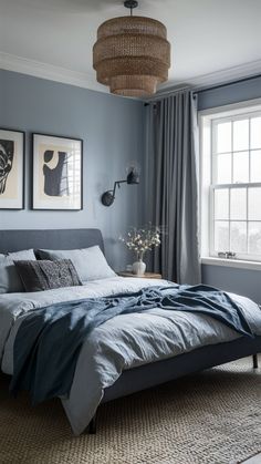 a bedroom with blue walls and gray bedding, two pictures hanging on the wall