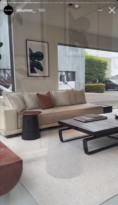 a living room with couches, tables and pictures on the wall behind glass doors