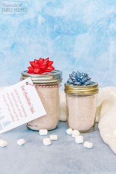 two mason jars filled with white marshmallows and a red bow