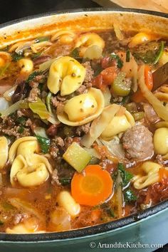 a large pot filled with pasta and meat soup on top of a stove burner