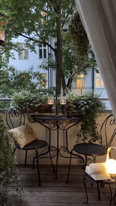 an outdoor table with two chairs and a lit candle on it in front of a window