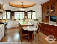 a large kitchen with wooden floors and white cabinetry, along with an oval dining table surrounded by chairs