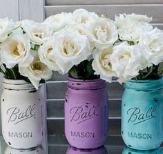 three painted mason jars with white flowers in them