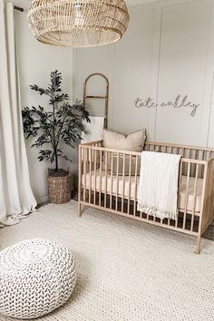 a baby's room with a wicker crib and round ottoman