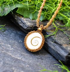 a necklace with a white shell and gold bead hanging from it's center