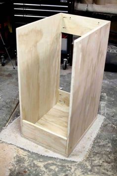 a wooden box sitting on top of a floor next to a piece of plywood