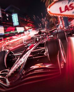 a red race car driving down a street next to a neon las vegas sign at night