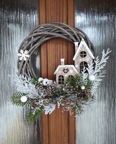 a christmas wreath hanging on a door with snowflakes and greenery around it