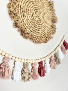 a wall hanging with tassels, beads and a straw hat on it's side