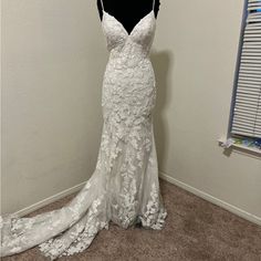 a white wedding dress on display in a room with a black mannequin behind it