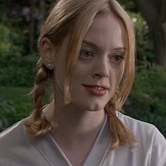 a woman with blonde hair wearing a white shirt and braid in front of her face