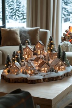 a lit up christmas village sits on a coffee table