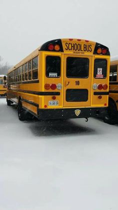 two school buses parked in the snow with one bus on its back and another behind it