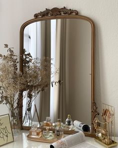 a mirror sitting on top of a table next to a vase