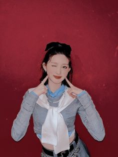 a young woman poses in front of a red wall with her hands on her hips