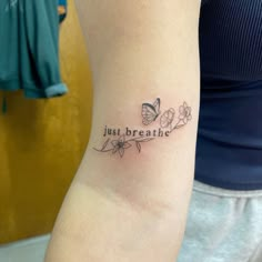 a woman with a tattoo on her arm that says just breathe and butterflies around it