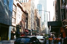 a busy city street with tall buildings on both sides and cars driving down the road