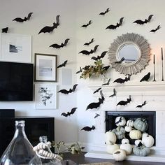 a living room decorated for halloween with bats and pumpkins on the fireplace mantel