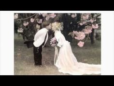 a bride and groom kissing in front of some trees with pink flowers on the branches