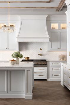 a large kitchen with white cabinets and gold trimmings on the ceiling, along with marble counter tops