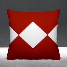 a red and white pillow sitting on top of a gray floor next to a wall