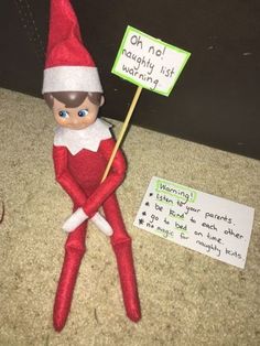 an elf holding a sign sitting on the floor next to a note that says oh no, i'm managing it wrong