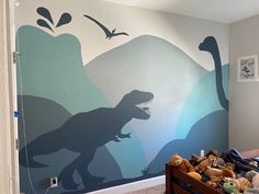 a child's bedroom with a dinosaur mural on the wall