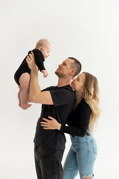 a man and woman holding a baby in their arms