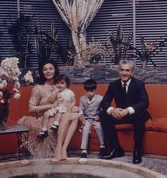 a family sitting on a couch in front of a fountain