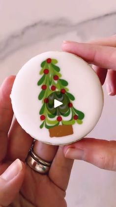 two hands holding a button with a christmas tree on it